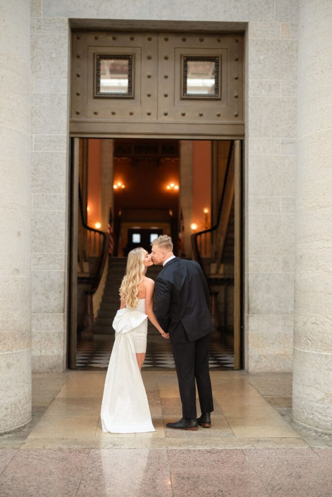 bride and groom kissing in doorway of the ohio statehouse