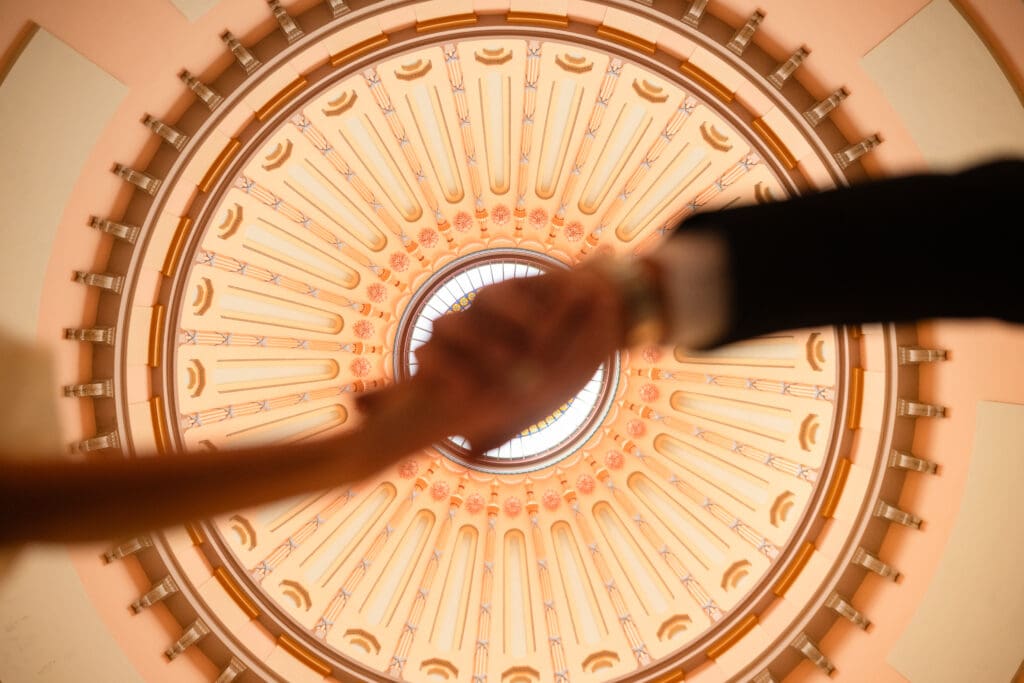 Ohio Statehouse Rotunda ceiling featured with couple holding hands during engagement session