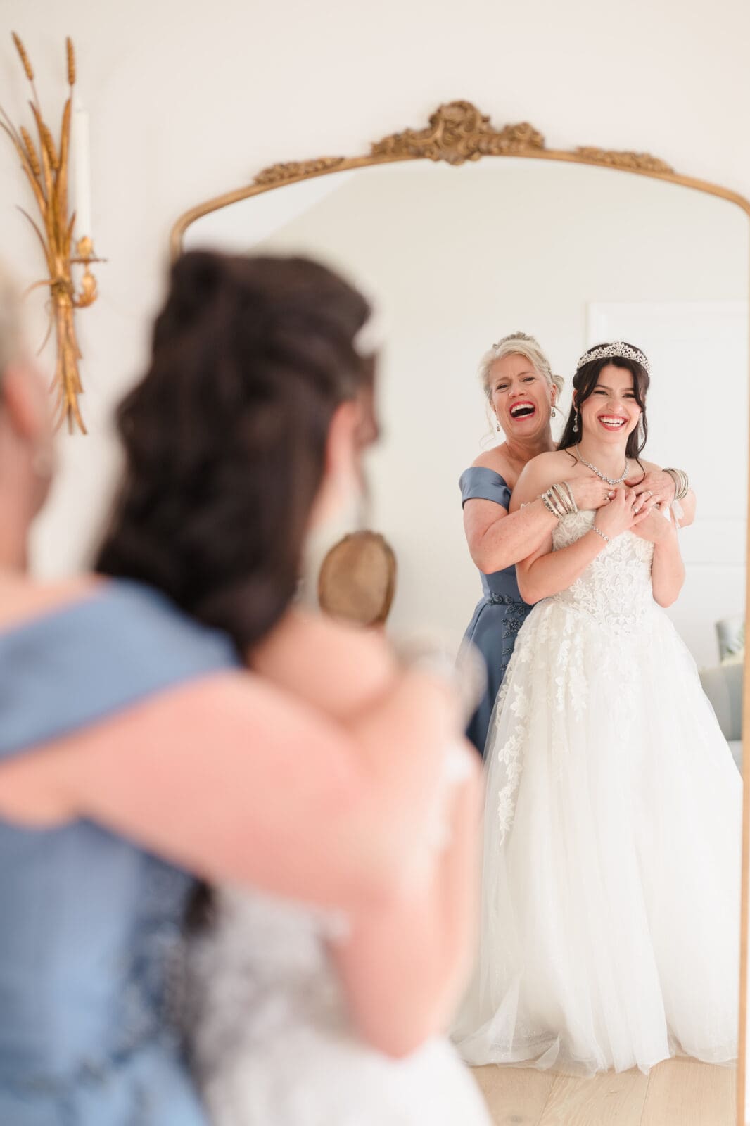 Mother and bride laughing and embracing while looking in the mirror at Aspen & Alston getting ready space Columbus wedding day