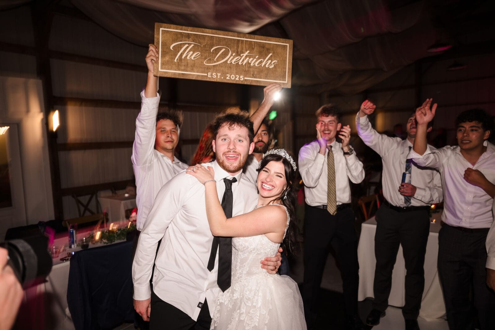 Joyful garden party wedding reception at Aspen & Alston with lively dance floor couple posing for photo with their custom sign