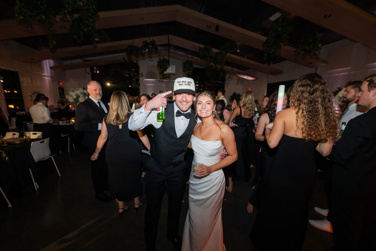 Bride and Groom pose with grooms new hat in the middle of their dance floor at Retreat 21
