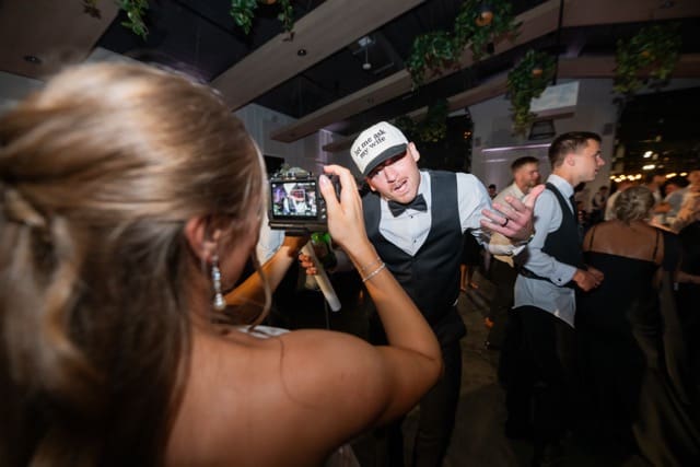 Bride records groom on videocamera while they are on teh dance floor
