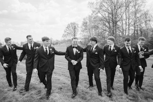 Groom laughing and walking with groomsmen outside Retreat 21