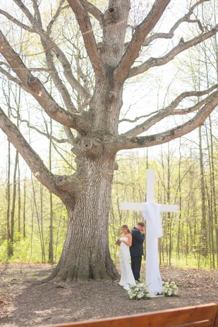 Couple sharing private vows during first touch at the big tree at Retreat 21