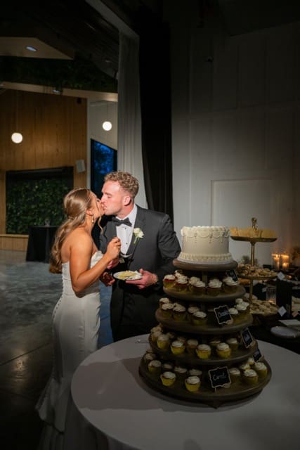Couple kissing after cutting cake at Retreat 21 wedding 