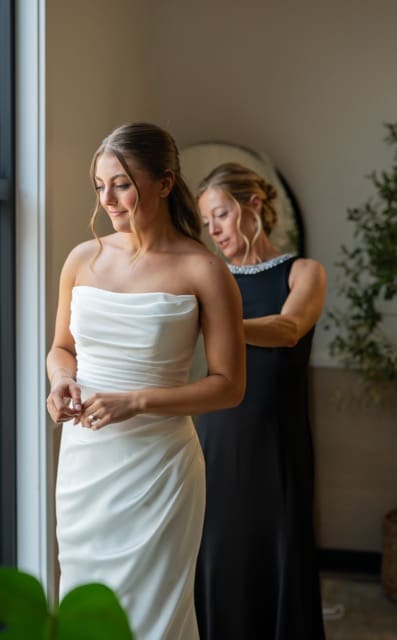 Bride and her mom while mom buttons wedding dress at Retreat 21 in bridal suite