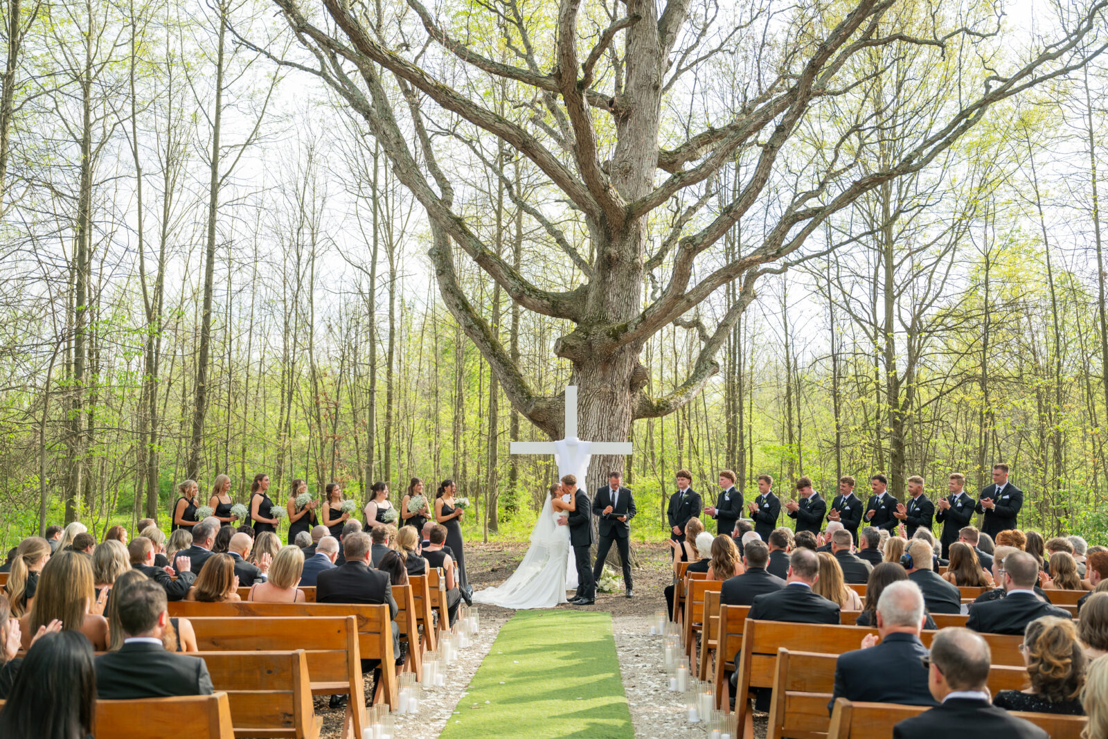 Couples first kiss with big tree as their backdrop of their outdoor wedding ceremony at Retreat 21